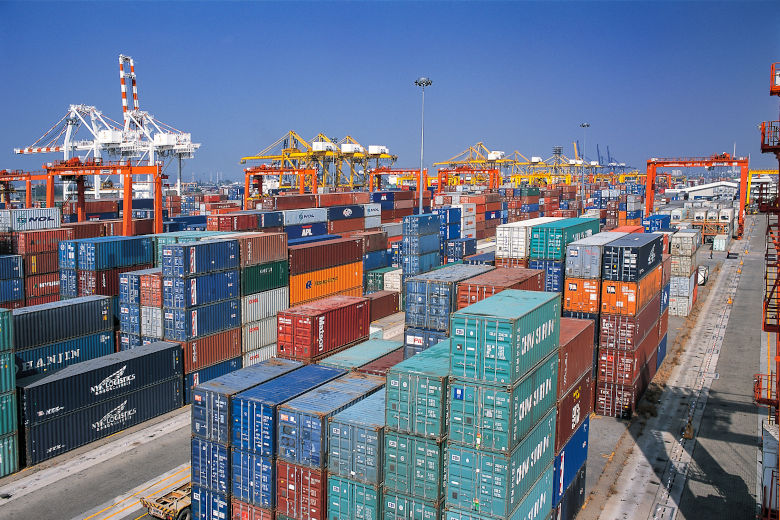 Åtskilliga containrar ligger staplade på varandra i en hamn. Foto.