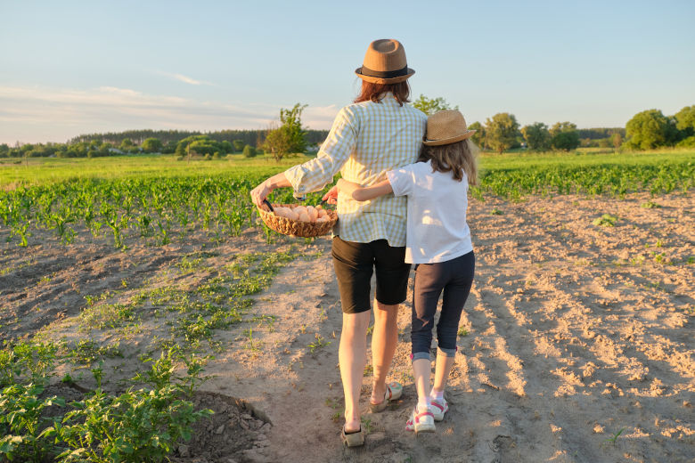 En mor och hennes dotter går tillsammans på åkermark. Foto. 