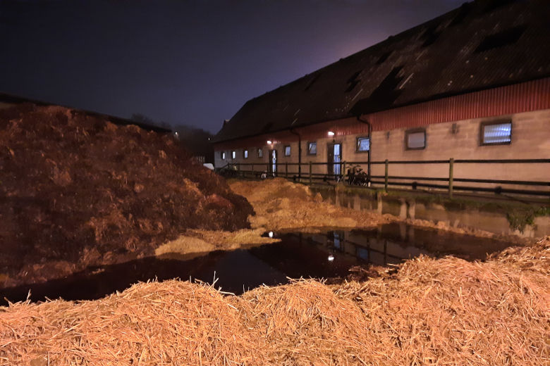 Högar av stallgödsel och halm ligger framför en bondgård. Foto.