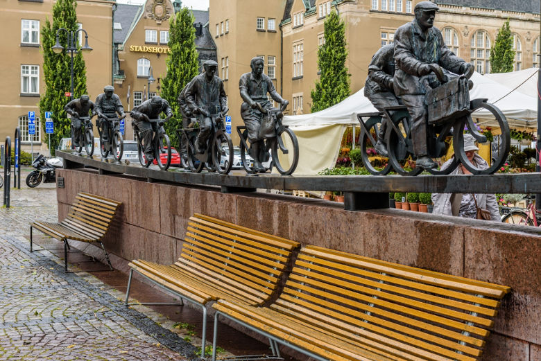 En staty av cyklister som står framför ett hotell. Foto. 