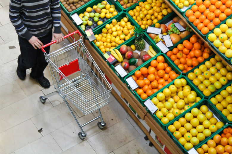 En kund i en mataffär kör sin kundvagn förbi fruktavdelningen. Foto.